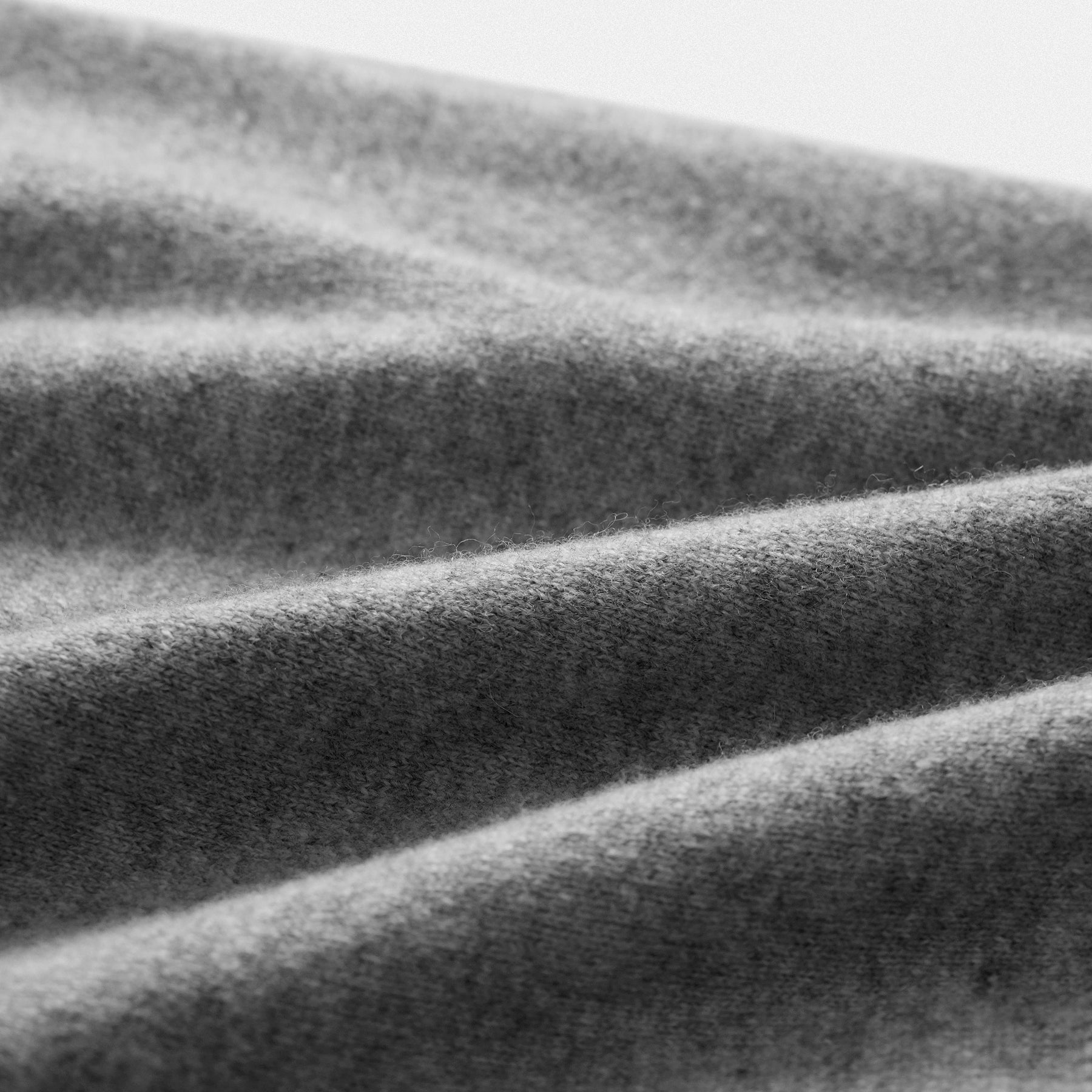 Dettaglio tessuto cardigan classico lana 100% grigio con collo rotondo e dettaglio cuore nero  