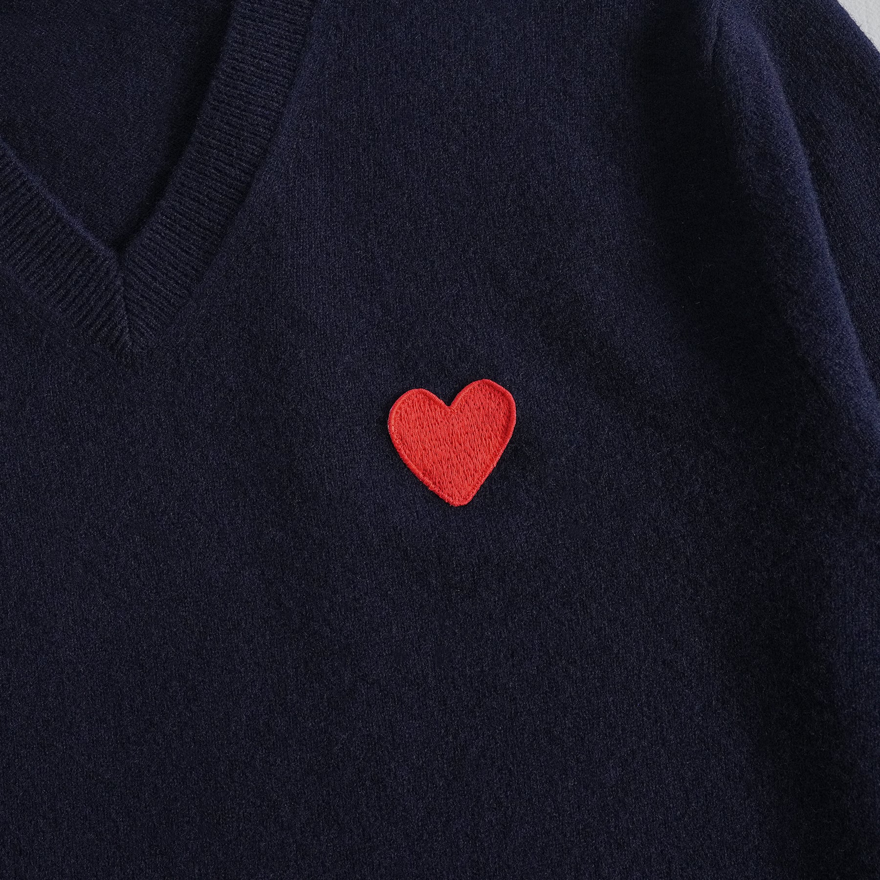 Dettaglio cuore scollo a V del pullover in lana 100% 