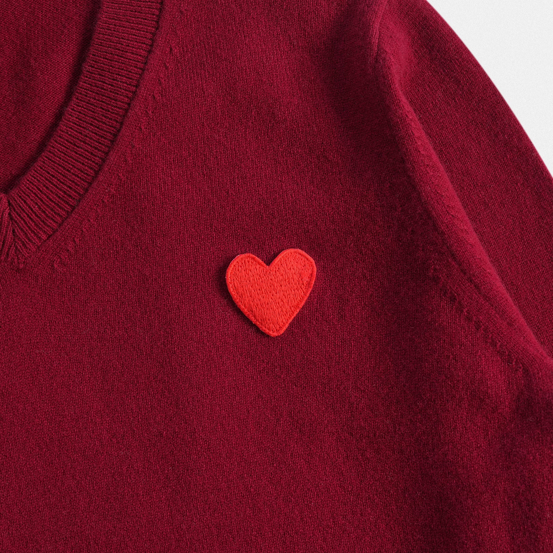 Dettaglio cuore classico unisex in lana 100% bordeaux con scollo a V e dettaglio cuore rosso vino