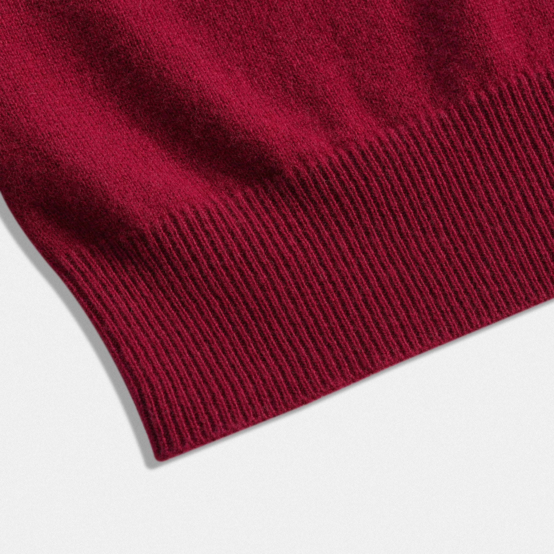 Dettaglio fondo classico unisex in lana 100% bordeaux con scollo a V e dettaglio cuore rosso vino