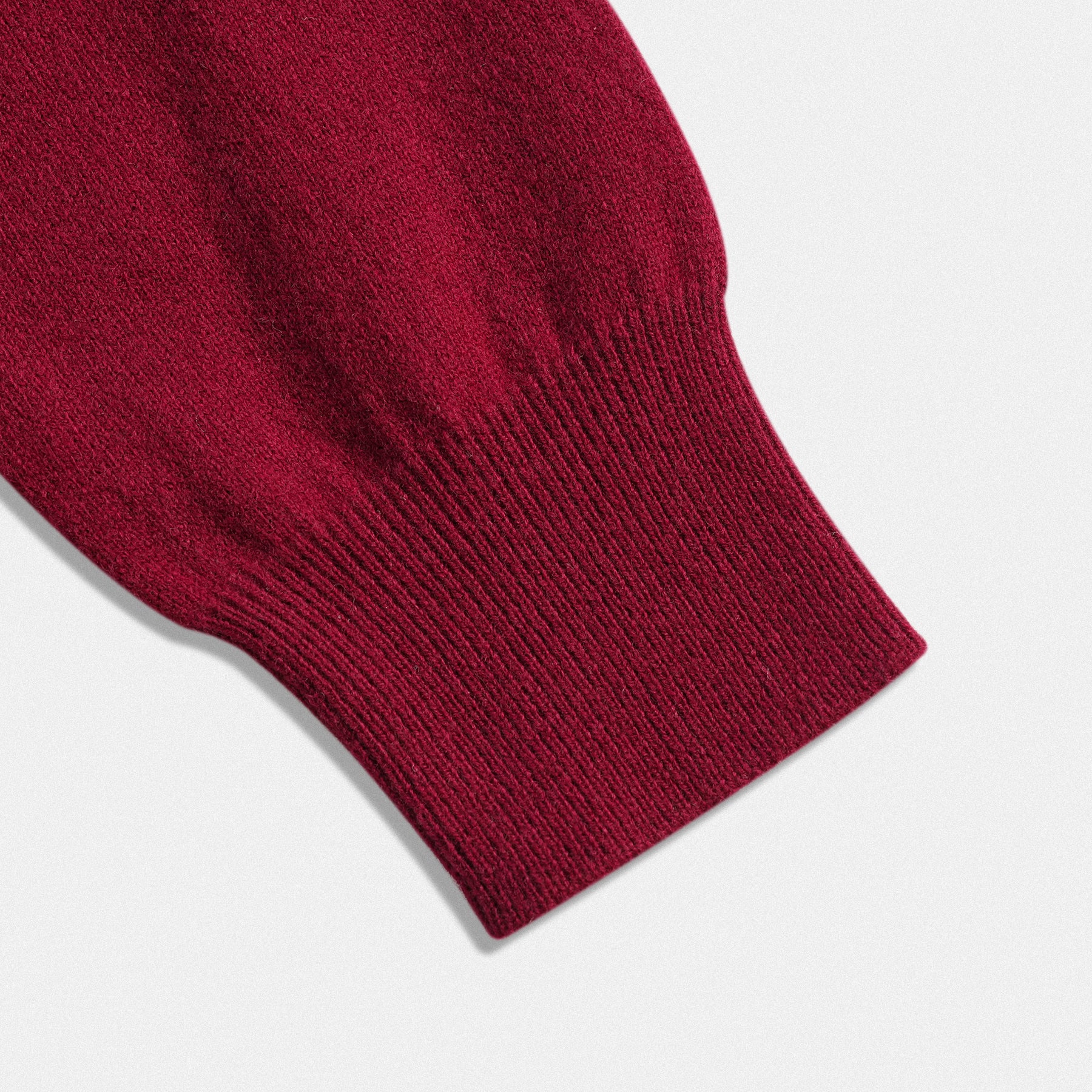 Dettaglio fondo manica classico unisex in lana 100% bordeaux con scollo a V e dettaglio cuore rosso vino