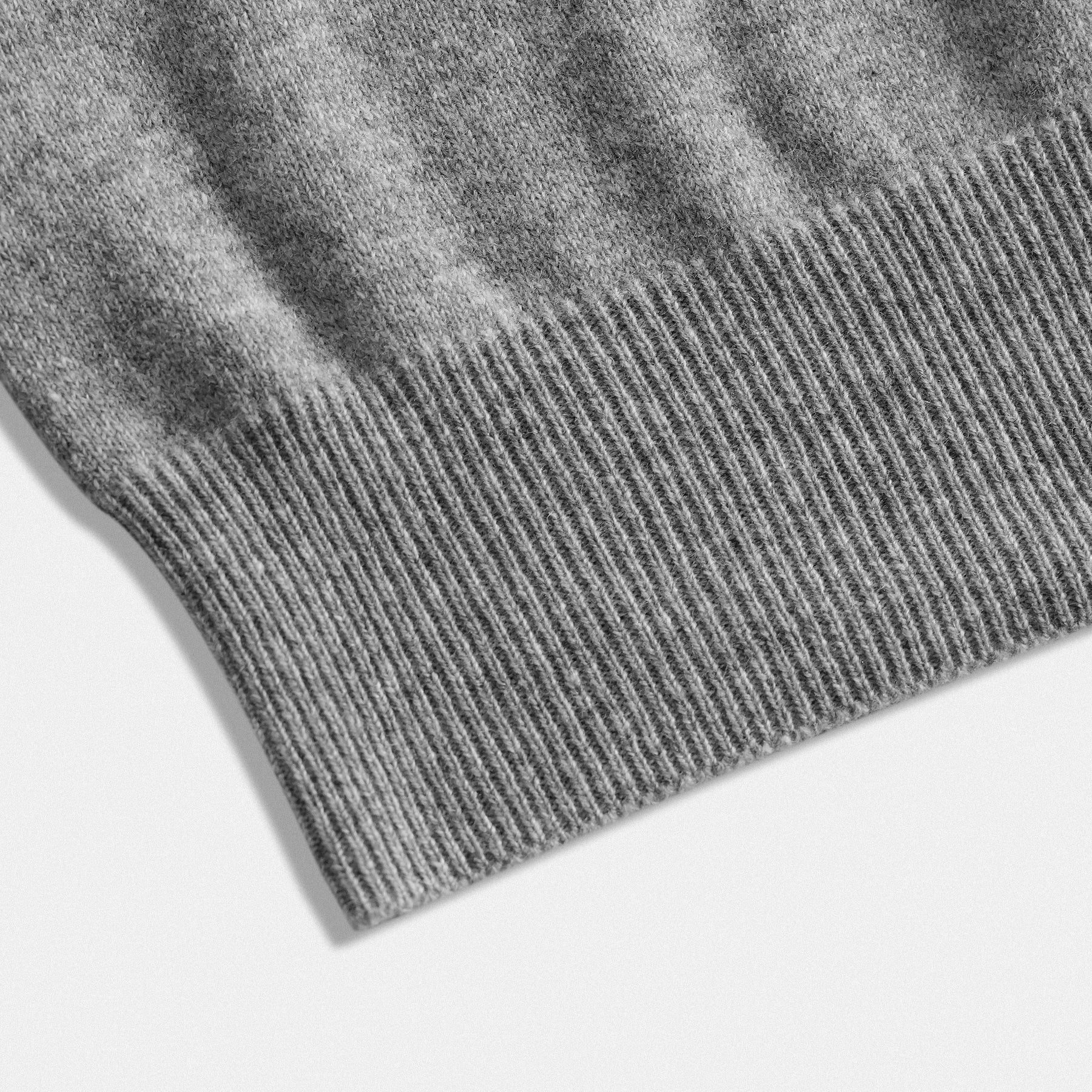 Dettaglio fondo cardigan classico lana 100% grigio con collo rotondo e dettaglio cuore nero  