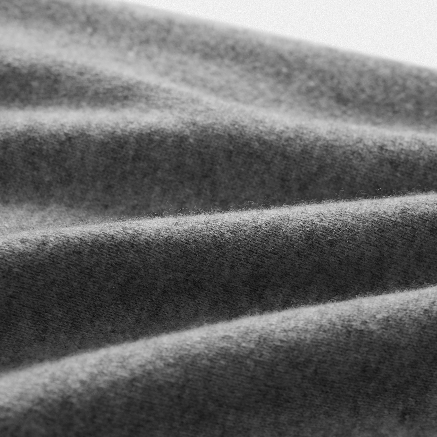 Dettaglio tessuto pullover classico uomo in lana 100% grigio con scollo a V e dettaglio cuore nero