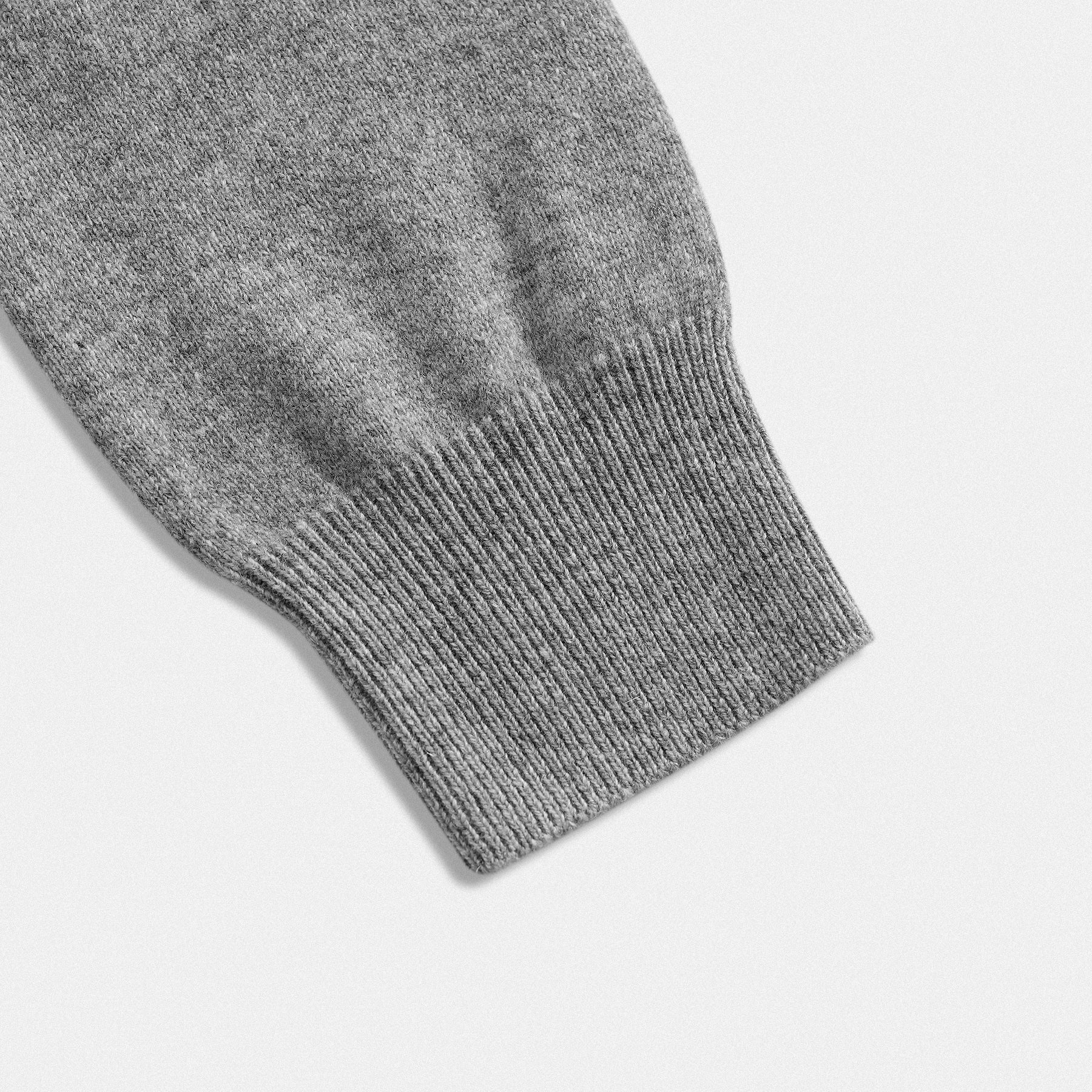 Dettaglio fondo manica cardigan classico lana 100% grigio con collo rotondo e dettaglio cuore nero  